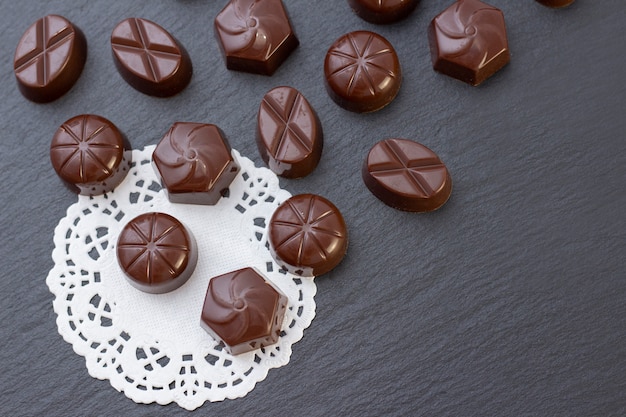 Chocoladesuikergoed op een zwarte oppervlakte, cacaopoeder. donkere foto, stemming.