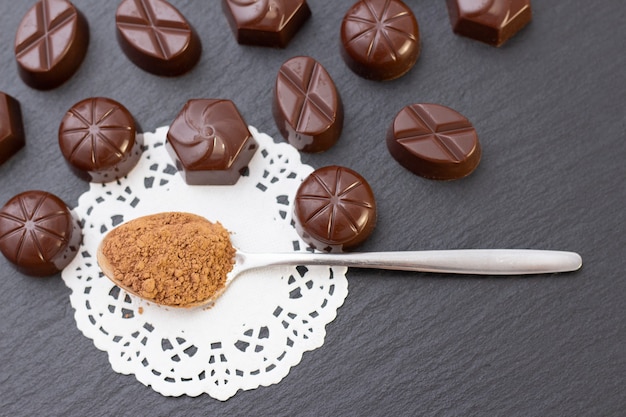 Chocoladesuikergoed op een zwarte oppervlakte, cacaopoeder. donkere foto, stemming.