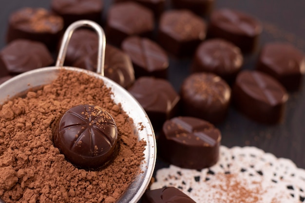 Chocoladesuikergoed op een zwarte oppervlakte, cacaopoeder. donkere foto, stemming.