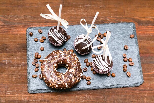 Chocoladetaart knalt versierde witte hagelslag op serveerbureau met donut donut koffiebonen op houten achtergrond, heerlijk gebak, desserts op stok. Lekker eten plat lag, lay-out, bovenaanzicht