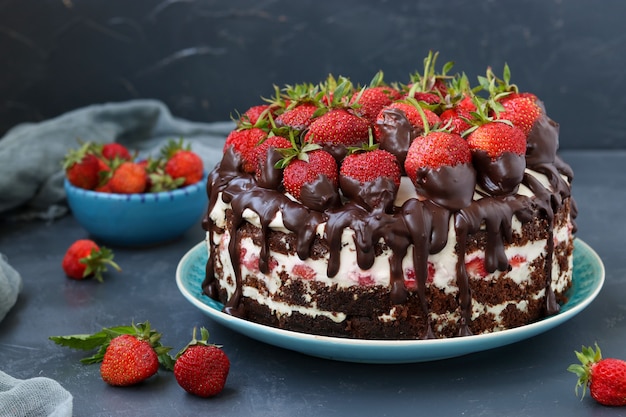 Chocoladetaart met aardbeien en room op een donkere achtergrond