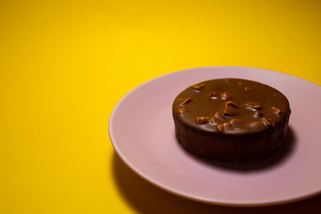 Chocoladetaartje met gezouten karamel op een roze bord Gele achtergrond bovenaanzicht