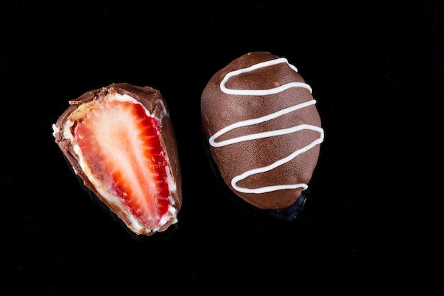 Chocoladetruffel met aardbeienvulling geïsoleerd op zwart.