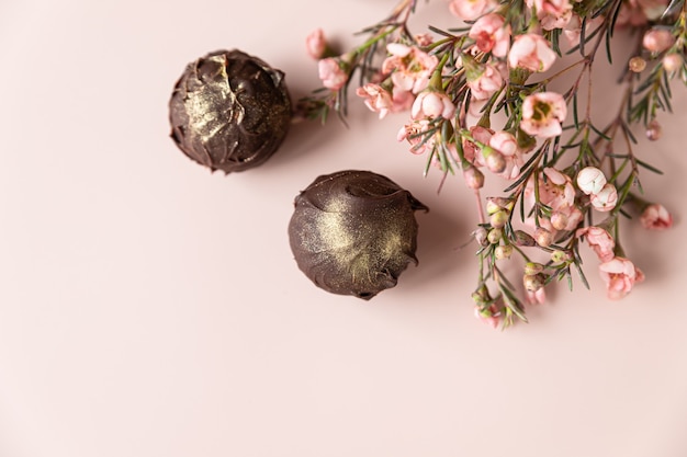 Chocoladetruffels op een roze achtergrond versierd met roze bloemen