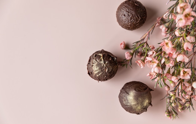 Chocoladetruffels op een roze ondergrond versierd met roze bloemen