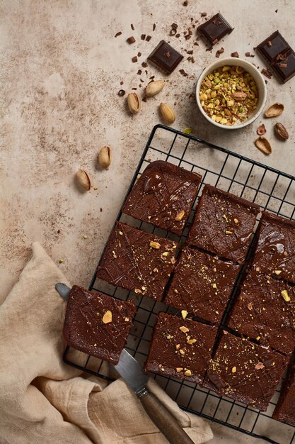 Chocoladevierkanten met pistachenoten en aardbeien op een metalen standaard op een lichte stenen achtergrond, bovenaanzicht, horizontale compositie. Plat leggen.