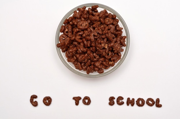 Chocoladevlokken in een kom en de tekst gaan naar school van de letters van het alfabet op een witte achtergrond