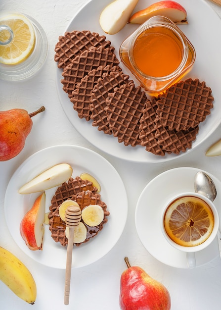 Chocoladewafels met rode peer, honing en banaan voor Ontbijt op witte achtergrond.