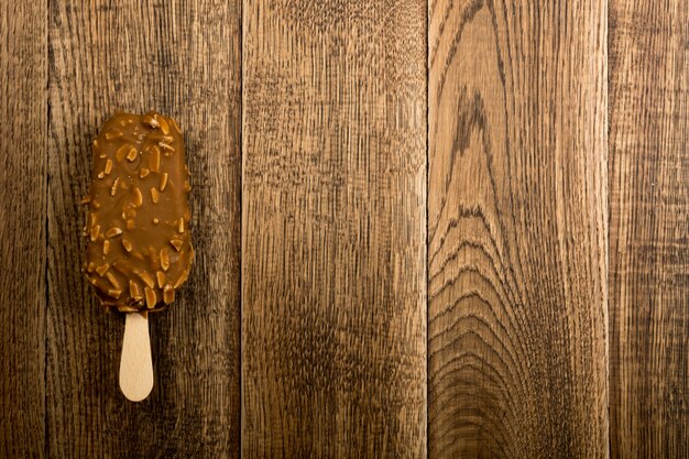 Barra di gelato del ghiacciolo della mandorla del cioccolato su fondo di legno