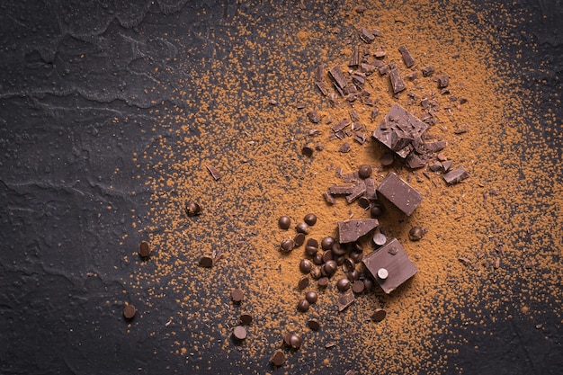 Chocolate background. Pieces and drops of chocolate, cocoa powder on black.