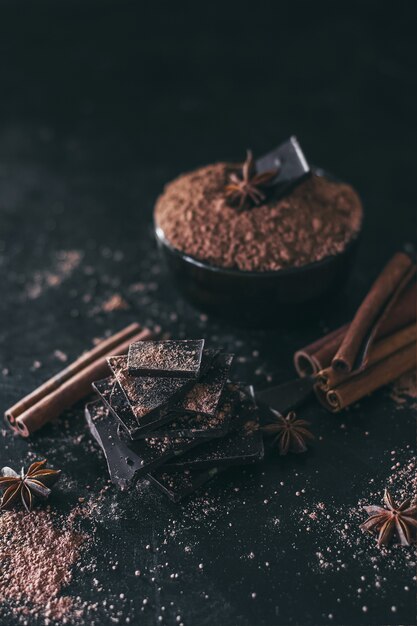 Foto pezzi di barretta di cioccolato con cacao in polvere su fondo scuro