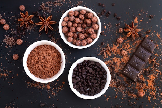 Chocolate bar pieces with ingredients for cooking sweet food on dark table top view