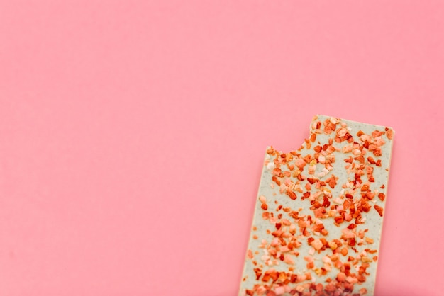 Chocolate bar with dried strawberry on a pink abstract background.