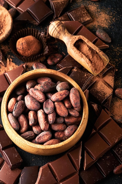 Chocolate bean cocoa Composition of cocoa powder bean cocoa bars and pieces of different milk and dark chocolate on black background Baking Chocolate Texture Top view with copy space Mock up