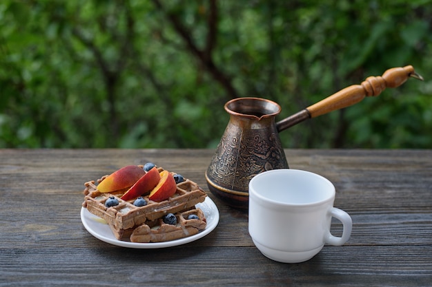 Waffle belgi al cioccolato con frutta, tazza di caffè e ceezve