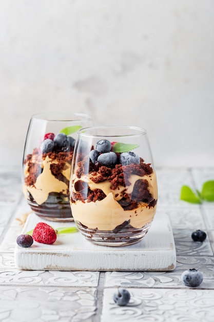 Chocolate biscuit dessert in glasses with raspberries and blueberries