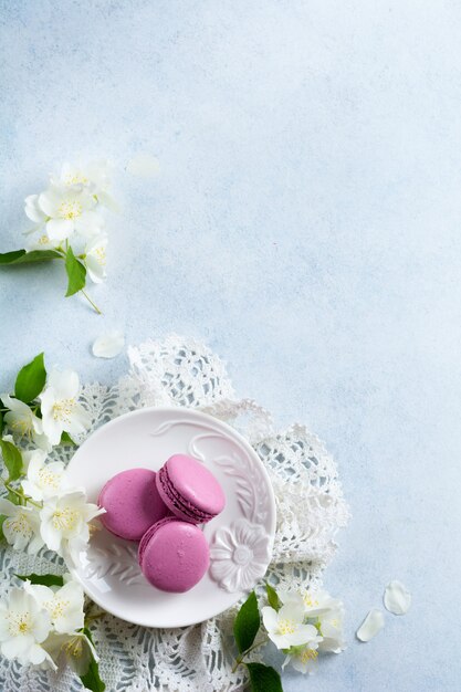 Chocolate and blackcurrant French macarons in ceramic plate on light concrete.  