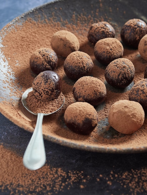 スプーンで暗い皿にカカオをまぶしたチョコレート ブリス ボール