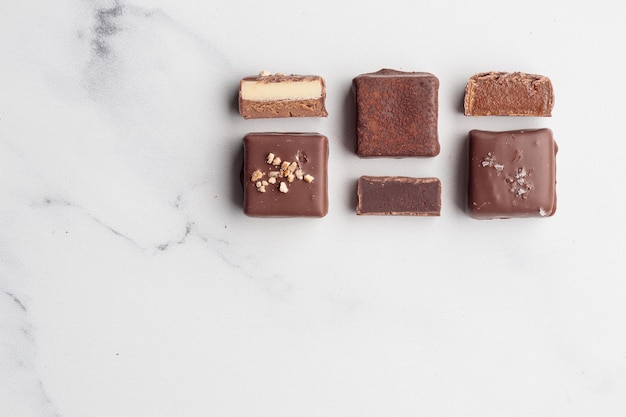 Chocolate bonbons with praline on white marble background