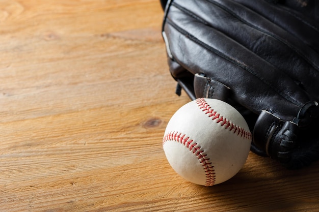 Chocolate brown baseball glove with baseball on wood board