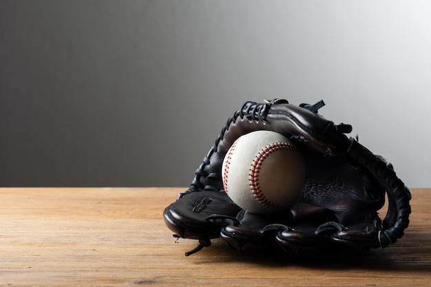 Chocolate brown baseball glove with baseball on wood board