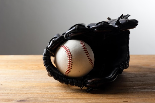 Chocolate brown baseball glove with baseball on wood board