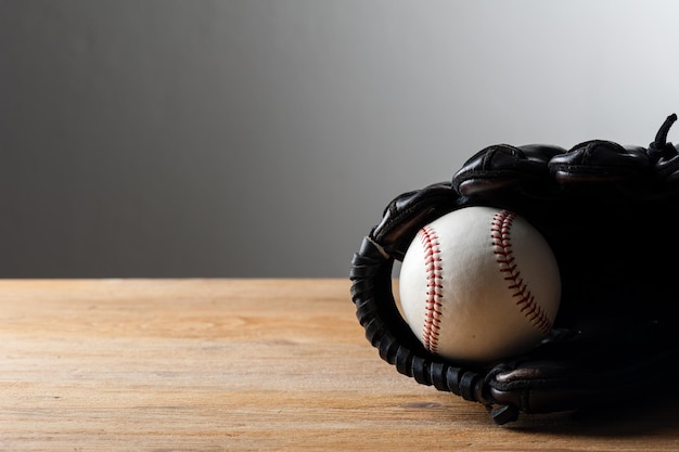 Chocolate brown baseball glove with baseball on wood board