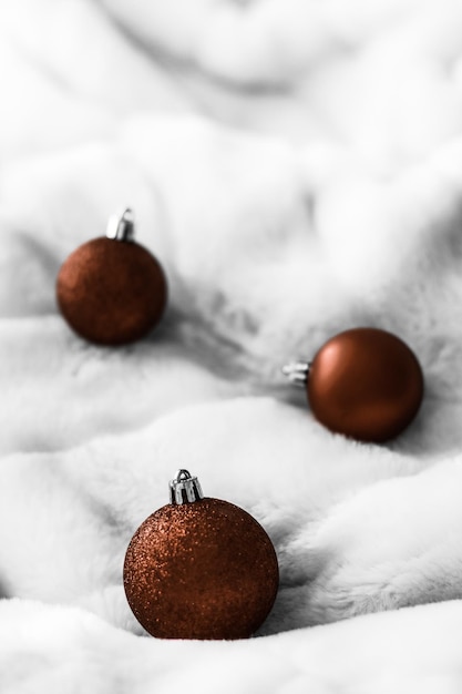 Chocolate brown Christmas baubles on white fluffy fur backdrop luxury winter holiday design background