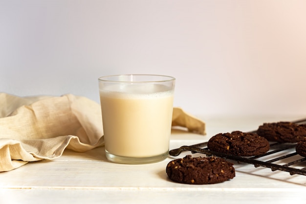 Chocolate brownie cookies and glass of coconut milk on wooden background. Homemade pastry.
