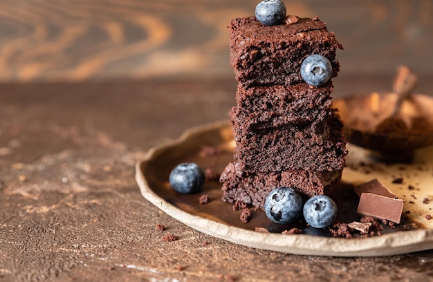 Quadretti di brownie al cioccolato decorati con mirtilli e pezzetti di cioccolato fondente e cacao in polvere