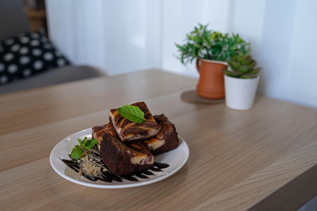 Brownie al cioccolato con salsa e noci decorato con foglia di menta su un accogliente tavolo di legno