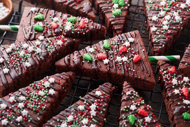 Chocolate brownies Christmas tree with chocolate icing and festive sprinkles on wooden table Christmas food ideas sweet homemade Christmas holidays pastry concept Holiday cooking concept Top view