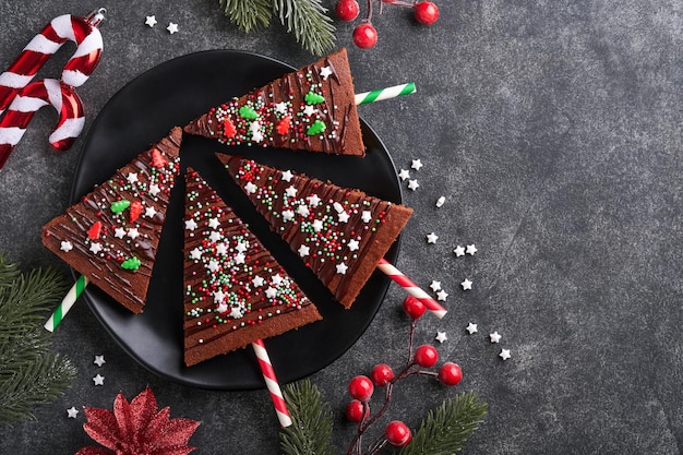 Photo chocolate brownies christmas tree with chocolate icing and festive sprinkles on wooden table christmas food ideas sweet homemade christmas holidays pastry concept holiday cooking concept top view