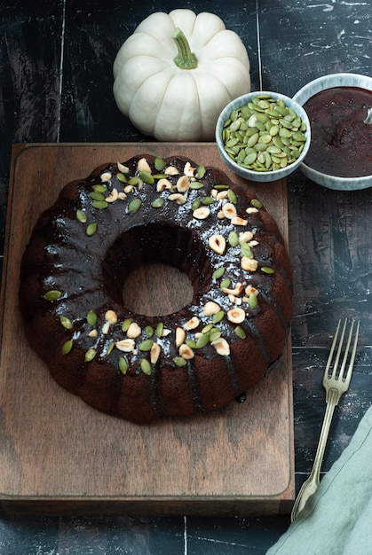 A chocolate bundt cake with a chocolate glaze and pumpkin seeds on top.