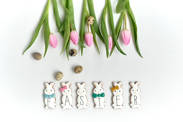 A chocolate bunny cookies with the quail eggs and tulips on a white background