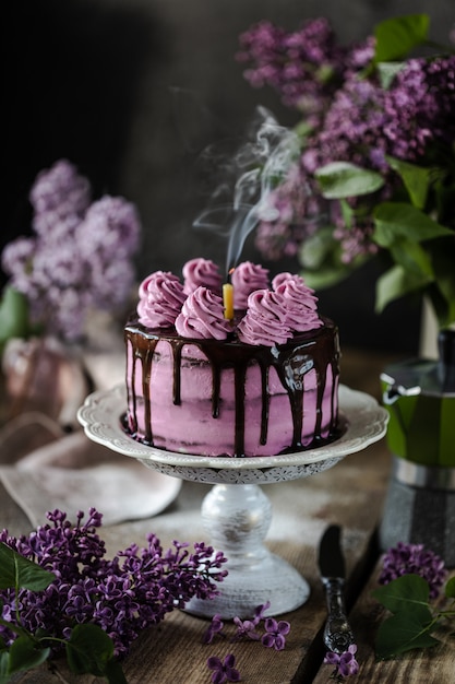 chocolate cake and a bouquet of lilacs on wooden table