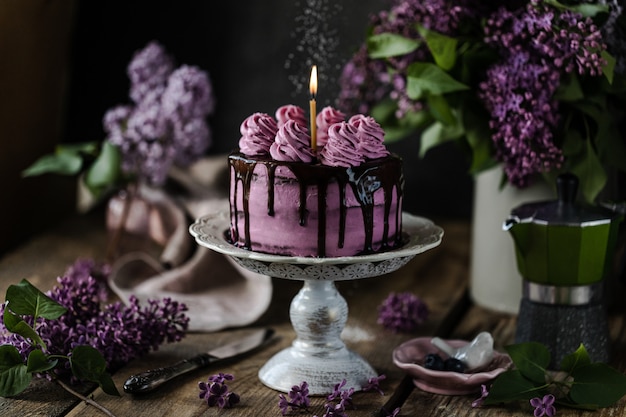 chocolate cake and a bouquet of lilacs on wooden table