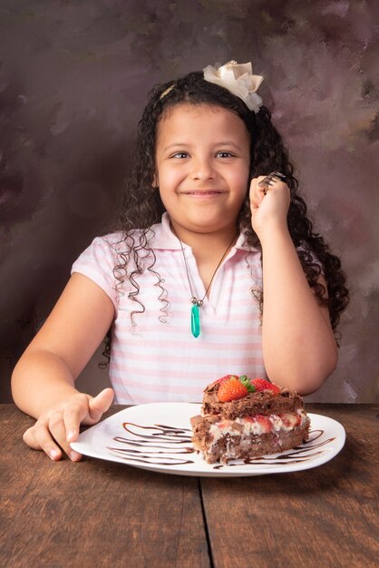 Photo chocolate cake, cute girl with beautiful piece of chocolate cake with strawberries, selective focus.