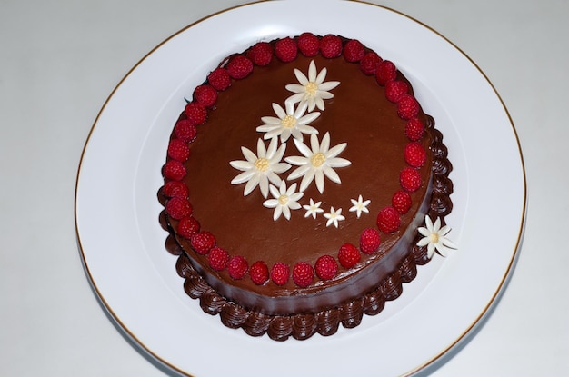 Chocolate cake decorated with fresh raspberries and fondant flowers