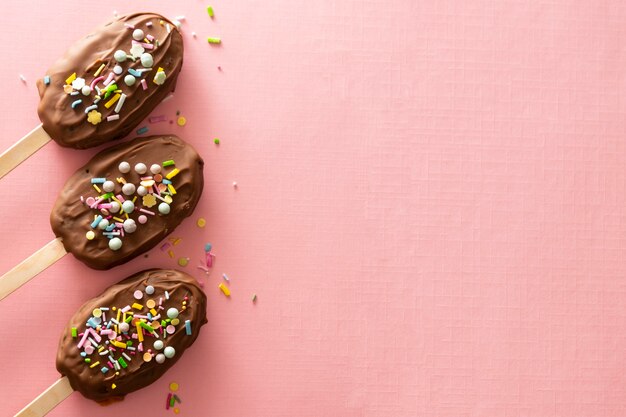 Chocolate cake dessert homemade lollies on pink background, top view