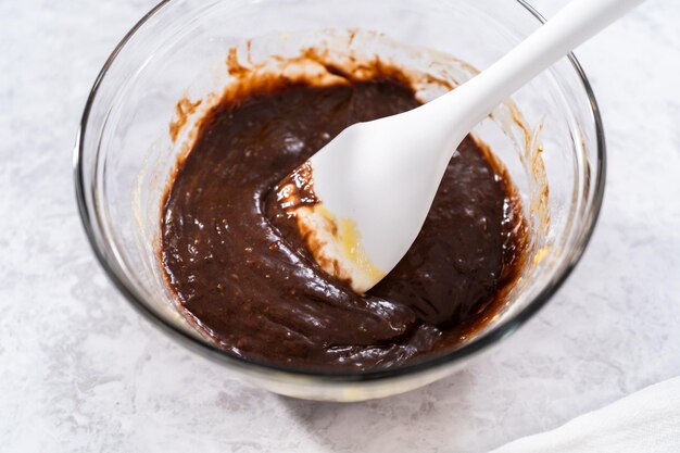 Chocolate cake dough in a glass mixing bowl on the counter.