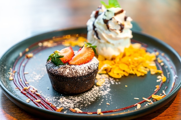 Photo chocolate cake lava with strawberry and vanilla ice-cream on black plate