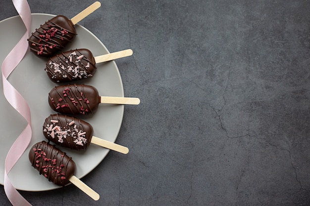 Chocolate cake pops in the form of ice cream on a stick  grey background Concept food sweets