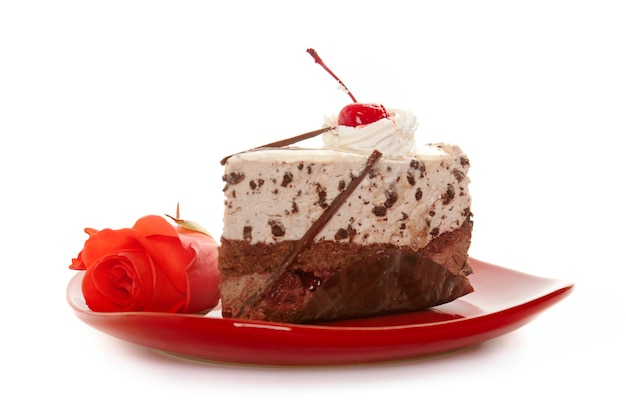 Chocolate cake on red dish with rose, isolated