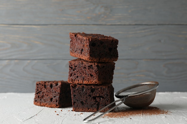 Chocolate cake slices and strainer on white table, close up