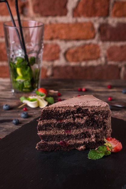 Chocolate cake on a stone plate on rustic wood table