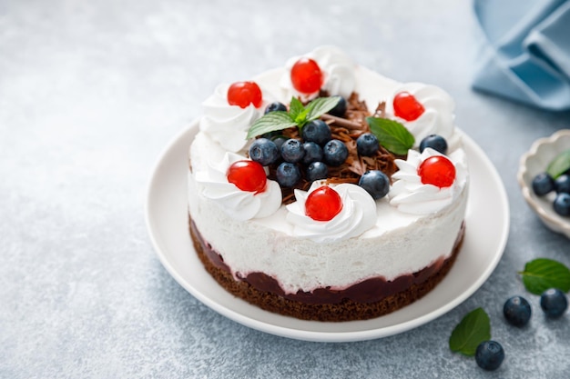 Chocolate cake white cheesecake decorated with blueberries cherry brown chocolate and whipped cream