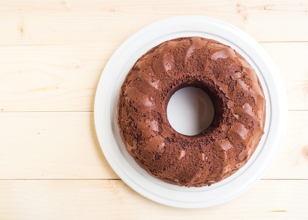 Chocolate cake on white plate. Over wooden table. 