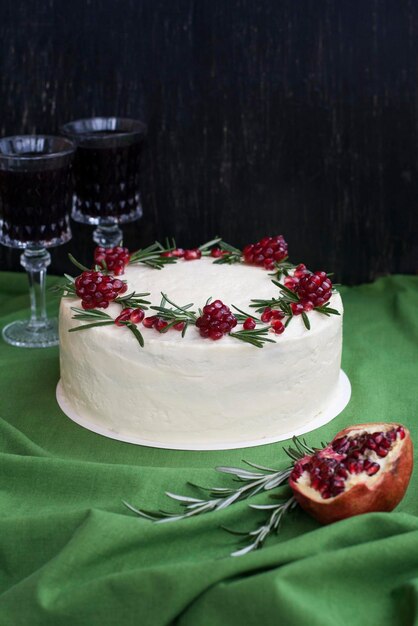 Chocolate cake with berry cream white cheese cream pomegranate berries and rosemary branches Two glasses of red wine Idea for a birthday cake or for a wedding cake