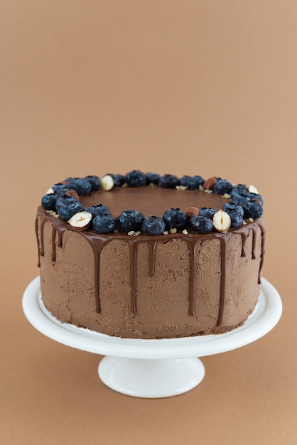 Chocolate cake with blueberries and nuts on a brown background